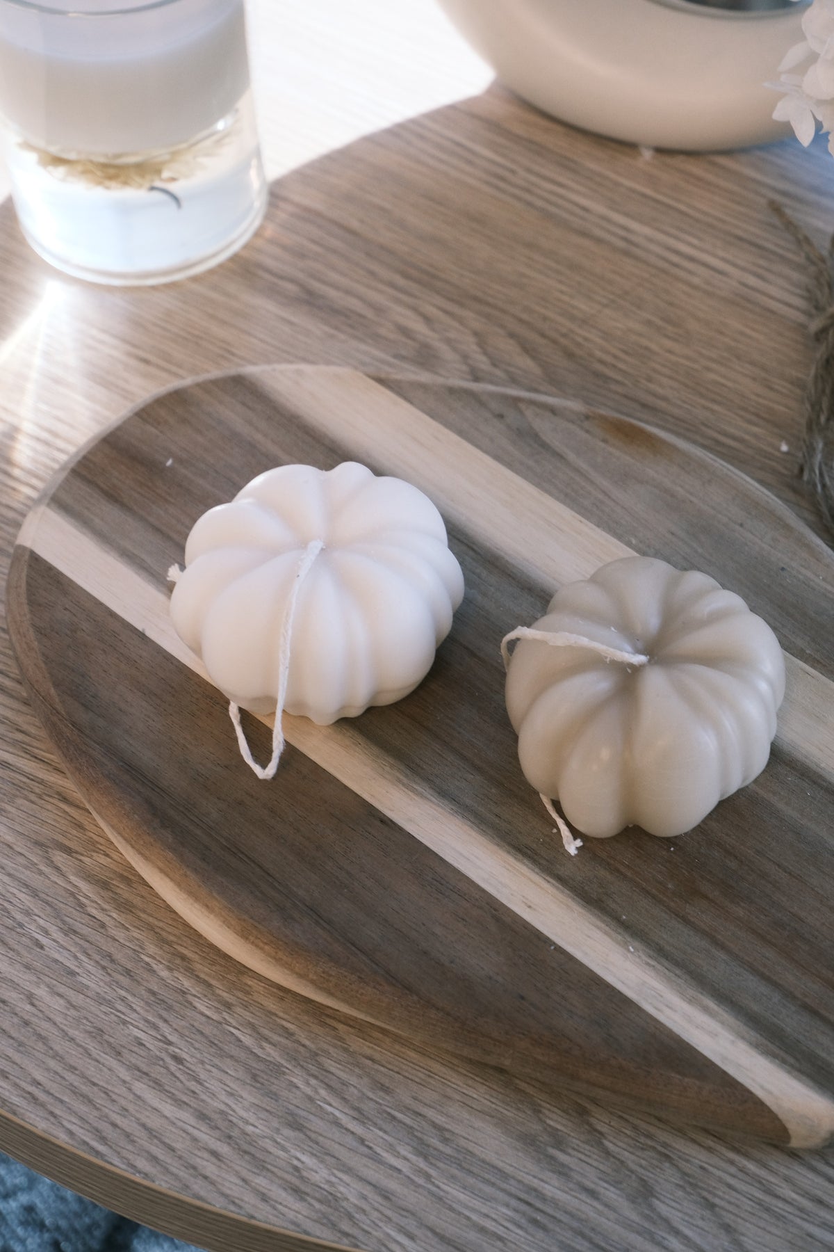 Two white pumpkins on a wooden cutting board