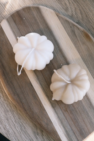 Two white pumpkin-shaped candles 