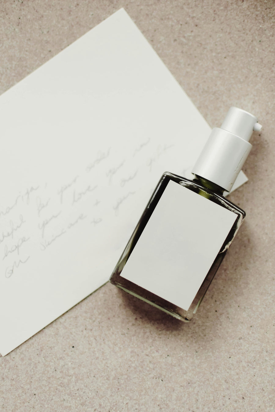 Perfume bottle with white cap on a beige surface